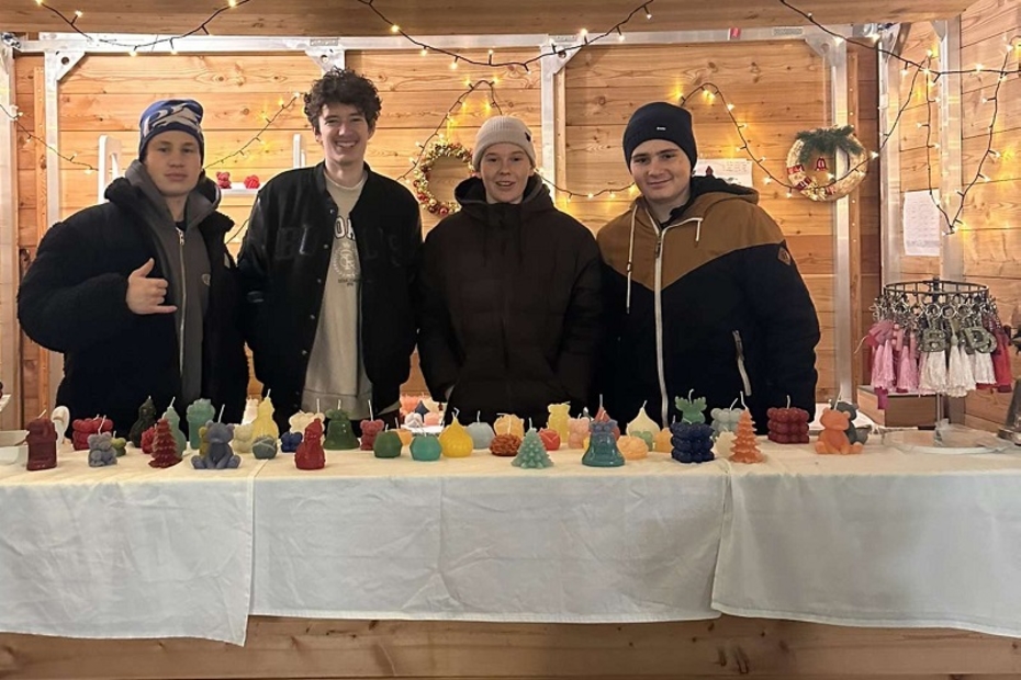 Vier Schüler stehen in hinter einem Weihnachtsstand und verkaufen Kerzen