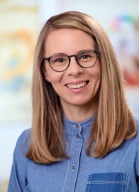 Portraitfoto einer Frau mit langen blonden Haaren und Brille